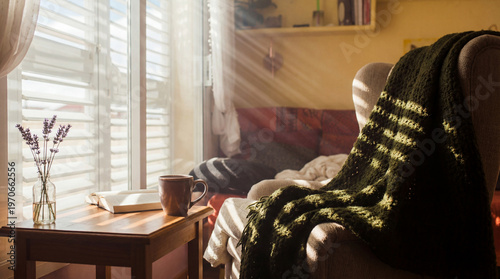 Quadro su tela Inviting cozy armchair in a sunlit living room corner with a green blanket, mug, book, and lavender