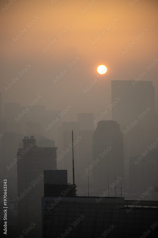 Naklejka premium Pollution-blanketed urban sunrise or sunset, and the thick haze is caused by high levels of air pollution, specifically fine particulate matter, PM2.5