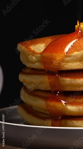 Freshly made pancakes drizzled with maple syrup served on a gray plate, American hotcakes