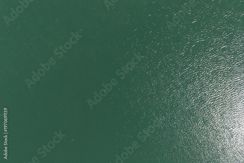 Obraz na płótnie Green water surface aerial view showing ripples and sunlight reflecting on the a