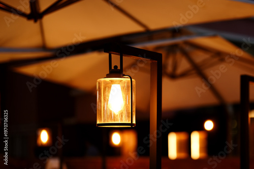 Low-angle view of lighting bulb hanging from parasol.