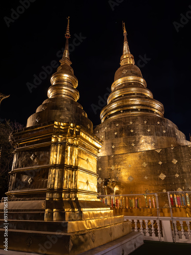 Принти на полотні Two resplendent golden chedis at Wat Phra Singh in Chiang Mai, Thailand, glow brilliantly against the night, showcasing exquisite traditional Buddhist architecture and spiritual grandeur