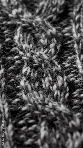 Close-up macro view of a black and white knitted textile background featuring intertwined wool threads, fuzzy fibers, and detailed stitch patterns in a monochromatic palette.