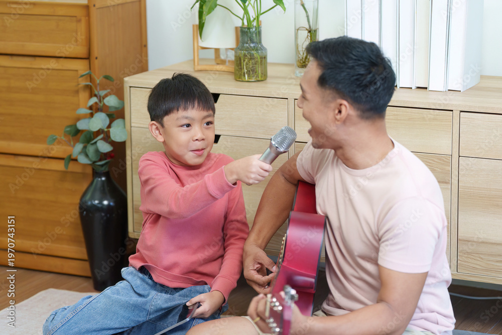Fototapeta premium Father and son bonding through music and singing at home