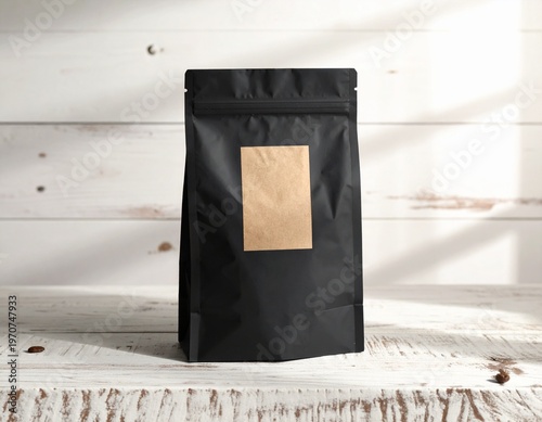 Blank black stand-up pouch with a customizable brown kraft label on a textured wooden background. Ideal for product mockups, branding, and packaging design concepts