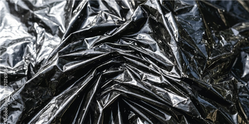 Close up view of crumpled black plastic sheet with sharp folds and reflective highlights creating a textured monochromatic surface pattern