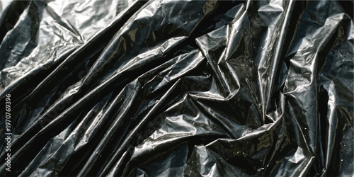 Close up view of black plastic garbage bag with deep folds and crinkles creating contrast highlights and shadows across the shiny synthetic surface texture