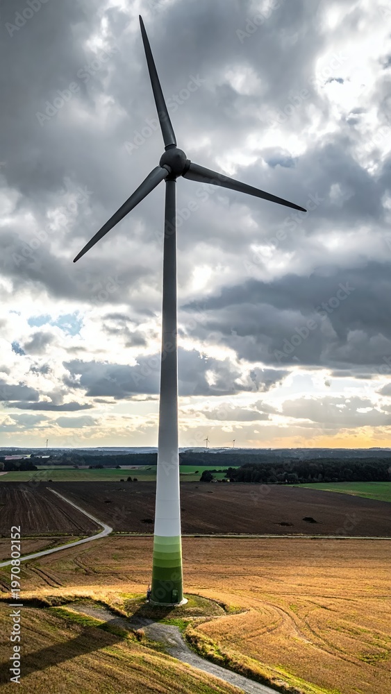 Obraz premium Wind Turbine Generating Clean Energy in Rural Landscape Under Dramatic Sky.