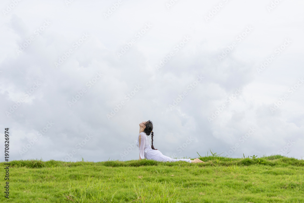 Fototapeta premium A Chinese woman practicing yoga on the grass