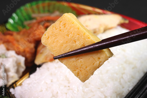 パック弁当から玉子焼きを箸で持ち上げる風景