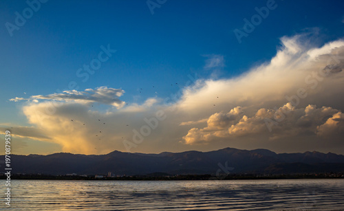 Dramatic sunset clouds over mountains with lake reflection