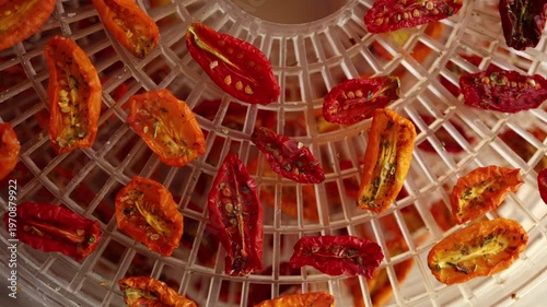 Bright red and yellow cherry tomatoes are arranged in a dehydrator, drying under warm air. This healthy method preserves their flavor, perfect for summer snacks.