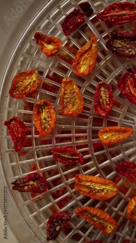 Bright red and yellow cherry tomatoes are arranged in a dehydrator, drying under warm air. This healthy method preserves their flavor, perfect for summer snacks.
