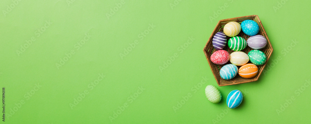 Obraz premium Multi colors Easter eggs in the woven basket on colored background . Pastel color Easter eggs. holiday concept with copy space