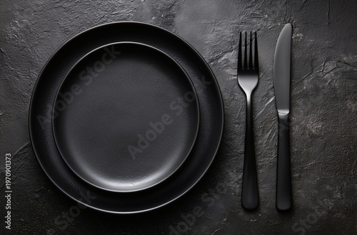 Minimalist Black Table Setting with Plates and Cutlery on Dark Textured Background