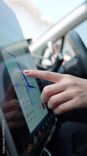 Woman's hand interacts with a modern car's touch screen navigation system for route planning. GPS map, destination, convenient driving technology concept. Vertical Shot