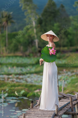 Woman In Conical Hat Holding Lotus On Wooden Pier, Thai Binh Vietnam