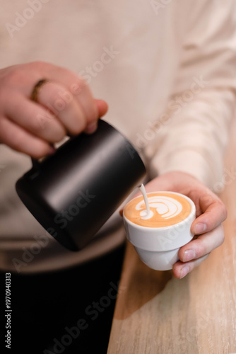 Barista pouring milk into a coffee mug, Close up barista hand pouring milk for making latte art in the cafe.