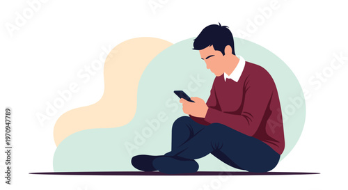 Young man sitting cross-legged on the floor and focused on using his smartphone against a soft abstract background.