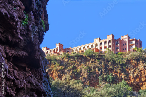 Moroccan hotel building on cliff overlooking ouzoud falls landscape, atlas mountains architecture