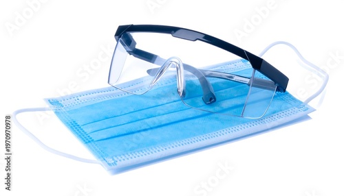 A medical mask and protective eyewear rest on a bright white background, symbolizing safety and health practices