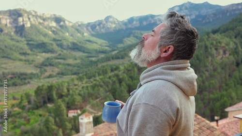 Mature man contemplating mountain views with coffee