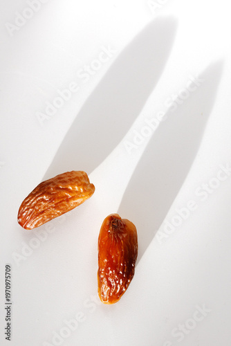 Close-up of two ripe dates on clean white background with sharp shadows