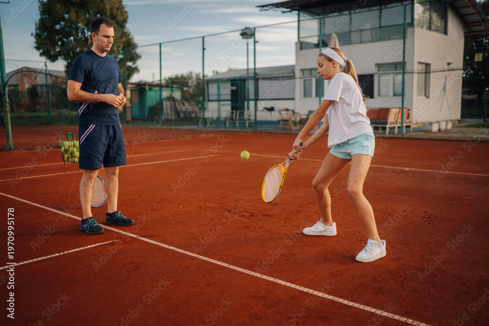 Obraz premium Coach training young girl playing tennis on clay court