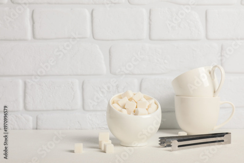 Bowl of sugar cubes with to...