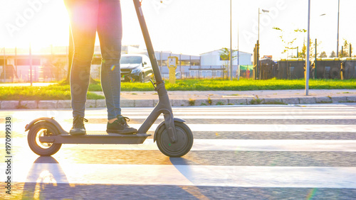 LENS FLARE: Modern girl rides through the suburbs on a cool high tech e scooter.