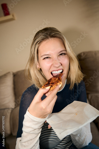 Young woman enjoying pizza slice at home