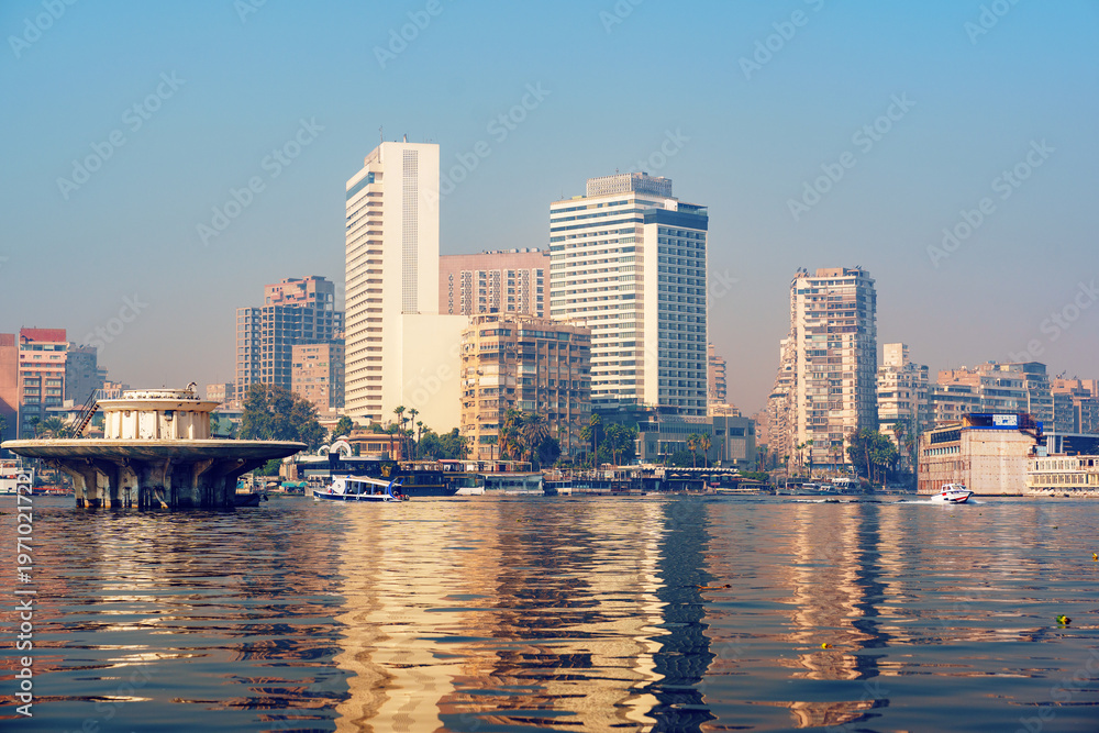 Obraz premium City skyline reflection on the Nile River with modern buildings in Cairo during a clear day
