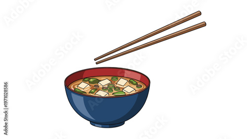 Bowl of hot miso soup with cubes of tofu and chopped green onions is shown with a pair of wooden chopsticks ready for a traditional meal.