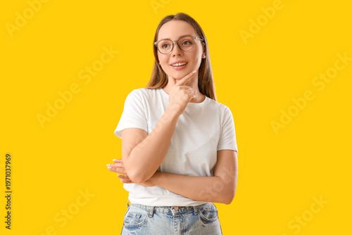 Dreamy young woman on yellow background