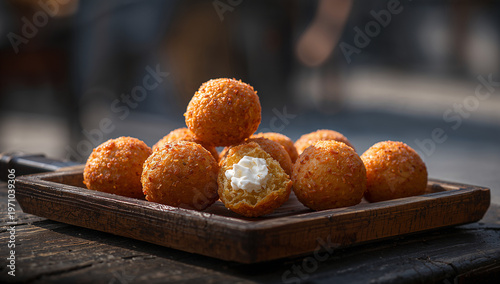 Fried cheese balls with a creamy filling, coated in crispy breadcrumbs, served on a rustic wooden board, food photography