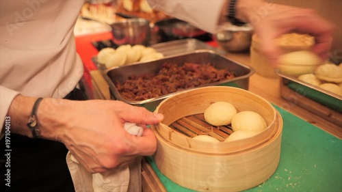 Chef placing bao buns in bamboo steamer