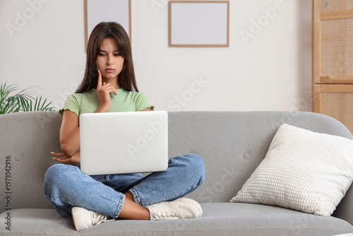 Thoughtful young woman usin...