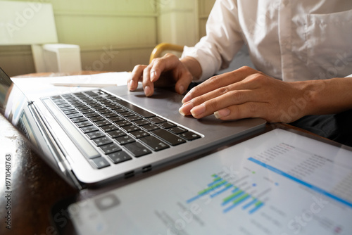 Принти на полотні businessman working on laptop computer and closes on hands typing keyboard documents and paper charts financial on the desk