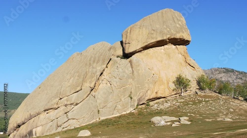 The Mongolian landscape. Picturesque rock in the shape of a large turtle on a background
of blue cloudless sky. The main attraction of the Gorkhi-Terelj National Park.