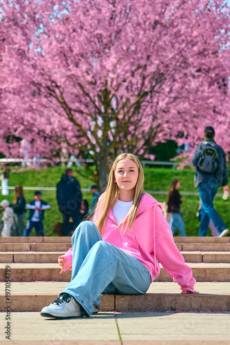 A girl walks through a park with flowering trees