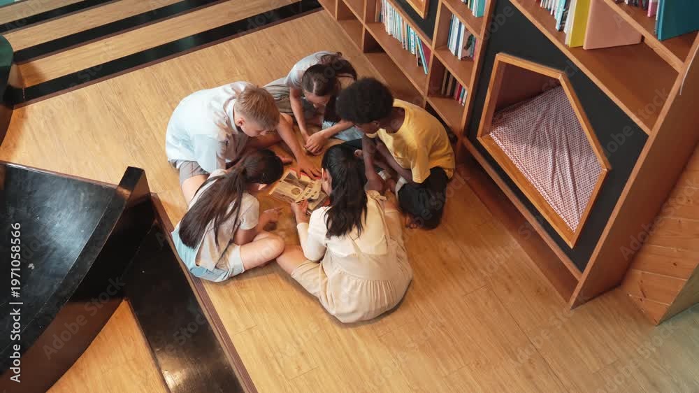 Group of diverse children sitting in circle while reading a book at ...