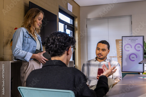 Diverse team meeting in office, man in plaid holding red phone, Tech monitor visible, copy space