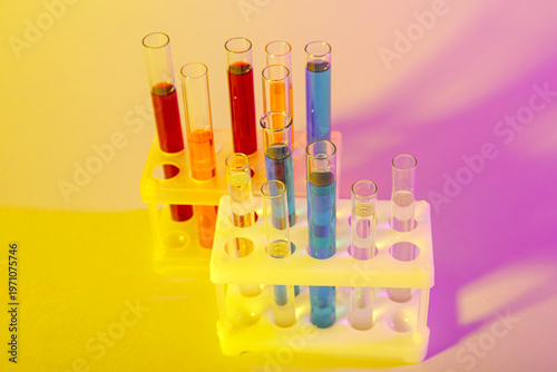 Test tubes with different samples in stands on colorful background