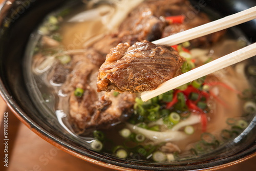 Foto Traditional Okinawa Soba noodle soup with pork belly and ribs in a black bowl