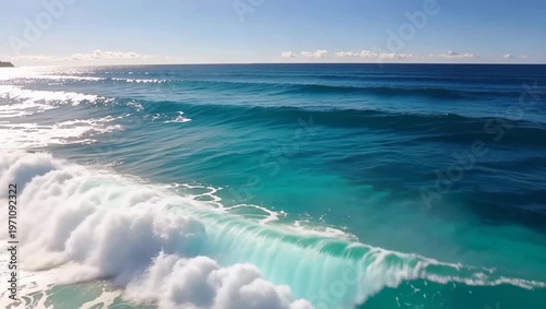 Beautiful ocean waves rolling towards the shore under a clear blue sky.