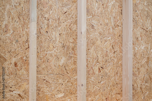 Fotografie Unfinished wooden wall with vertical studs and oriented strand board panels in c