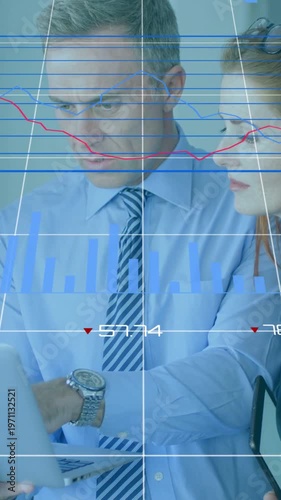 Vertical video: Two analysts reviewing finance at desk man tapping tablet charts cycling to analyze