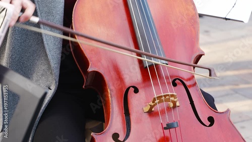 Cellist plays in outdoor area with smooth motions in different frames showing the instrument and bow techniques