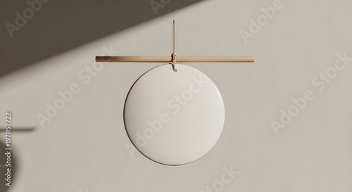 Clean minimalist circular white sign mock-up with a subtle natural wood hanger, suspended against a neutral beige wall, beautifully illuminated by a diagonal shadow and soft sunlight, providing an ele