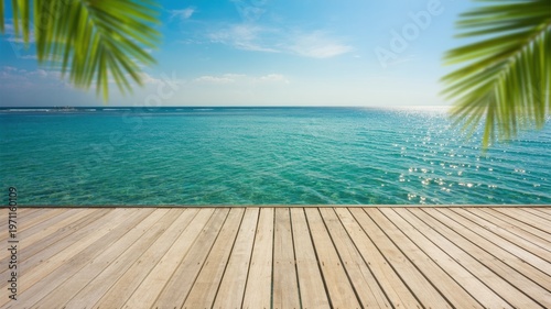 Expansive view of a serene tropical ocean with clear turquoise water from a beautiful wooden pier on a bright sunny day framed by lush green palm leaves